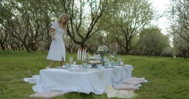 Çok hoş bir piknik sahnesi, güzel düzenlenmiş bir masa seti sergiliyor, gür ve canlı bir meyve bahçesi alanında.