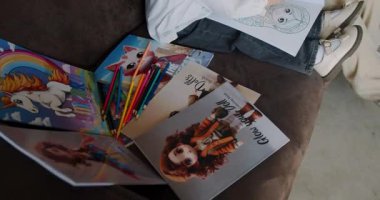 Hoş boyama kitapları ve rahat bir koltukta sergilenen kalemlerden oluşan canlı ve renkli bir koleksiyon.