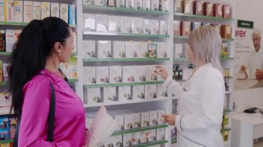 Kadın, çeşitli doğal ürünlerle dolu bir sağlık mağazasında çalışan bir eczacıdan uzman tavsiyesi ister.