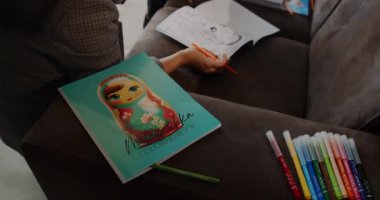 Bir sanatçı renkli kalemler kullanarak ve sanat yaratmak için kitaplar çizerek canlı bir renk etkinliğine katılır.