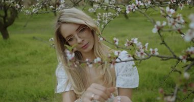 Genç bir kadın, güzel çiçeklerle çevrili güzel bir meyve bahçesinde huzurlu bir anın tadını çıkarır.