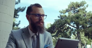 Odaklanmış bir profesyonel, doğanın tadını çıkarırken bir tablet kullanır.