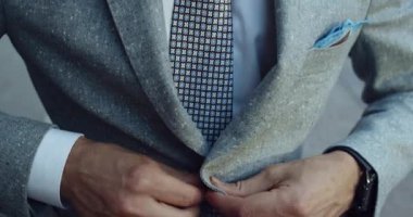 İyi giyimli bir bireyin şık takımlarını ve zarif kravatlarını titizlikle ayarladığı yakın çekim görüntüsü.