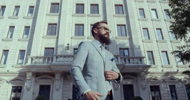 Zarif bir binanın dışına özgüven saçan iyi giyimli bir adam. İş ve moda teması için mükemmel..