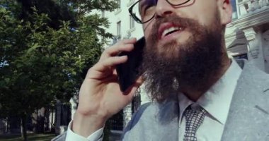 Modayı takip eden bir işadamı canlı bir şehir ortamında telefonuyla canlı bir konuşma yapıyor.