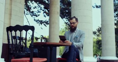 Özel dikim takım elbiseli bir işadamı başarısını ve başarılarını sergilemek için tabletini açık havada neşeyle kullanır.