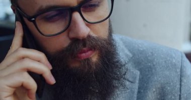 Takım elbiseli düşünceli bir adam açık havada akıllı telefonuyla derin bir sohbete daldı.