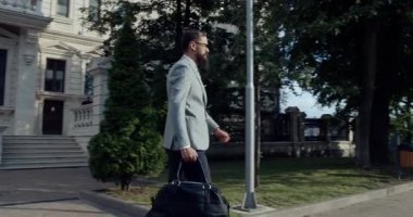 Bir iş adamı, şehir ortamında profesyonel tarzını sergileyen bir çantayla güvenle adım atar..