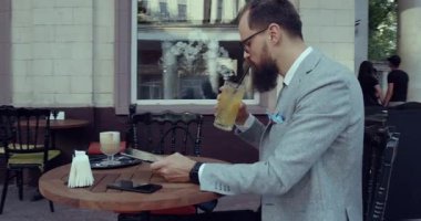 Takım elbiseli profesyonel bir adam bir kafede içki içerken rahatlar.