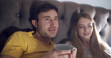 Rahatlamış bir çift birbirine sokulur, samimi ortamlarında büyüleyici bir film gecesinin tadını çıkarırlar.