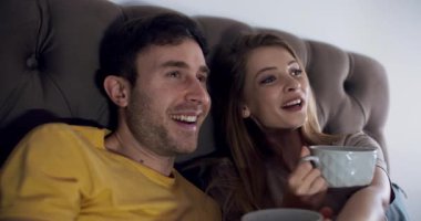 Bir çift mutlu bir şekilde rahat bir kanepede rahatlıyor, kahkahalarını, içkilerini paylaşıyor ve bir filmden zevk alıyorlar.