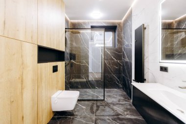 Bu şık banyo modern bir banyo, uygun bir tuvalet, parlak bir lavabo ve duvarda büyük, yansıtıcı bir ayna içeriyor.