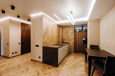Bu modern mutfak ahşap aksanlar, modern cihazlar ve rahat bir atmosfer için ortam aydınlatması içerir.