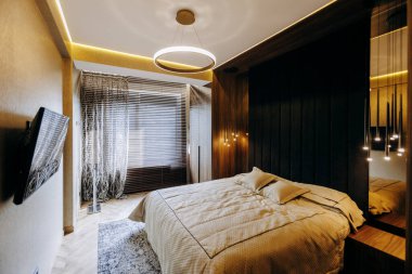 Şık bir yatak odası tasarımı rahat bir yatağı, şık modern ışıklandırması ve zarif dekorasyon unsurları olan renkli bir mekan sergiliyor.