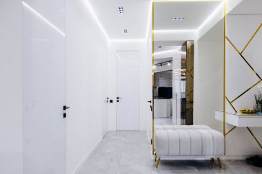 Duvarın yüzeyine asılmış şık bir aynayla süslenmiş ahşap bir bankın bulunduğu uzun bir koridor.