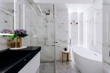 Banyoda rahat bir küvet, işlevsel bir lavabo, geniş bir duş ve uzayı güçlendiren zarif tasarlanmış bir ayna var.