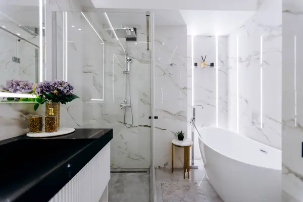 Banyoda rahat bir küvet, işlevsel bir lavabo, geniş bir duş ve uzayı güçlendiren zarif tasarlanmış bir ayna var.