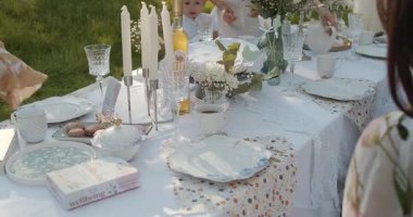 Zarif bir porselen, titreyen mumlar ve zarif bir çiçek dekoru içeren güzel bir açık hava yemek masası.