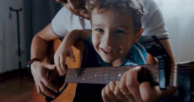 Genç bir çocuk babasıyla özel bir anı paylaşıyor. Kucağında gitar çalmayı öğreniyor. Aralarındaki bağı ve müziği gösteriyor.