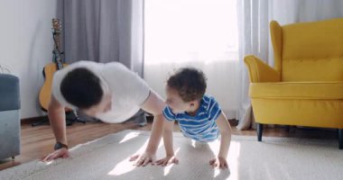 Bir adam ve küçük bir çocuk, keyifli bir antrenman müsabakasına girişip, takım çalışmasını sergiledikleri rahat oturma odalarında özel bir anı paylaşıyorlar.