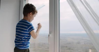 Genç bir çocuk pencereden dışarı dikkatlice bakar. Çocukluk masumiyetini somutlaştıran camı çizerken yaratıcılığını ifade etmek için güneş ışığından esinlenir.