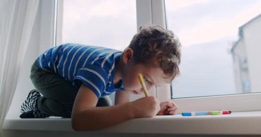 Bu yürek ısıtan video, bir pencere pervazında otururken sanatla yaratıcılığını ifade eden genç bir çocuğu sergiliyor.