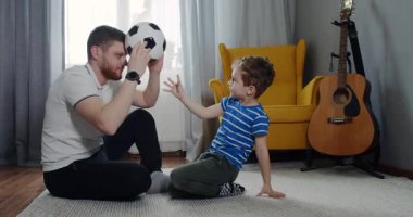 Bir baba ve oğul, rahat oturma odalarında futbol oynayıp, kahkahalarını ve güçlü bağlarını samimi bir videoda yakalıyorlar.