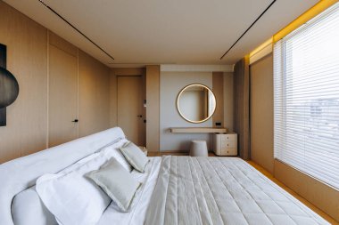 Bir yatak odasında, duvarda asılı zarif bir ayna ile güzelce yerleştirilmiş geniş bir yatak var.