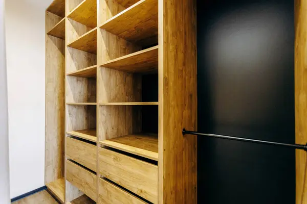 Güzel işlenmiş ahşap raflar ve çekmeceler içeren geniş bir dolap. Ek stil için zarif siyah bir kapı ile tamamlanmış.