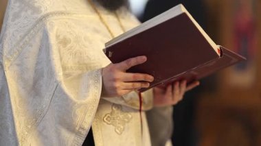 Sakallı bir adam kutsal metne ve öğretilerine dalmış bir şekilde kilisede oturmuş İncil okuyor.