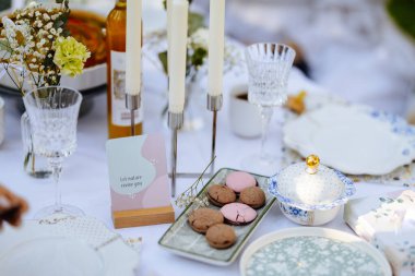 Masanın üzerinde düzgünce yerleştirilmiş tabaklar, hafifçe titreşen mumlar ve nefis kurabiyeler var.