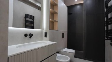 Lavabo, tuvalet, taharet musluğu ve ferahlatıcı bir duş alanı gibi gerekli malzemelerle modern bir banyo. Rahatlamak için sakin bir yer yaratıyor.