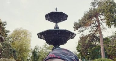 Bu video, selfieler, bank oturma ve meditasyon yoluyla atmosferden zevk alan bir adamın yer aldığı bir fıskiyeyle huzurlu bir park sunuyor.