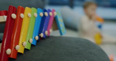 Bebek oyuncakları keşfeden yürek ısıtan bir video. Çocuğu neşeyle ksilofon çalarken, renkli oyuncaklarla kanepede otururken ve bir oyuncağı çiğnerken gösteriyor.