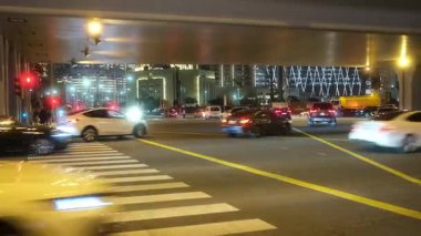 Köprünün altından geçen arabalarla bir şehir caddesi gece uğulduyor. Gece hayatını aydınlatan farlar ve yoğun yol sesleri.