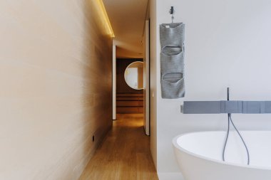 Geniş bir küvetin olduğu bir banyo ve yakınlardaki duvara güzelce yerleştirilmiş bir havlu.