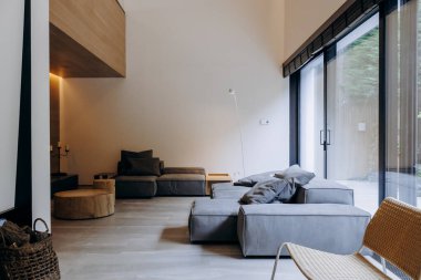 Konforlu oturma odasında rahat bir kanepe, davetkar bir sandalye ve doğal ışık sunan güzel cam kapılar var.