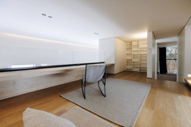 Konforlu bir oturma odası ortamında, dekoratif bir halıya yerleştirilmiş rahat bir sandalye var, rahatlamak için davetkar bir ortam yaratıyor.