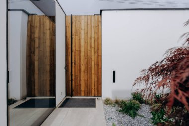 Uzun, dar koridorda, güzel yapılmış ahşap bir kapı var, bozulmamış beyaz bir duvara karşı dizilmiş, özelliklerini geliştiren.