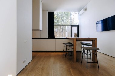 Güzel bir ahşap masa ve ona uygun tabureler olan rahat bir oturma odası ve bolca ışık sağlayan geniş bir pencere.