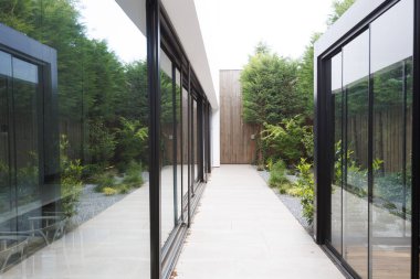 Geniş ve uzun bir koridor, iki ayrı bina arasında uzanır, sayısız büyük pencerelerle süslenir, içeri bol güneş ışığı alır.