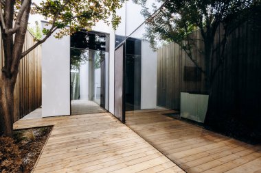 Güzel, ahşap bir yürüyüş yolu zarif bir şekilde büyüleyici bir eve götürür, arka planda dingin bir zemin sağlayan uzun ağaçlarla.