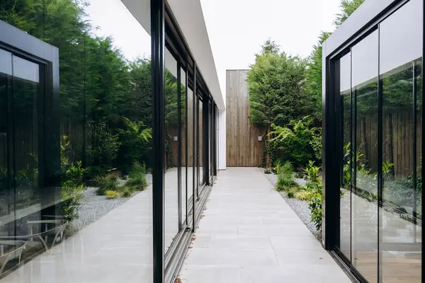 Arkasında zarif bir şekilde güzel bir eve giriş imkanı sağlayan geniş cam kapıların bulunduğu uzun ve geniş bir koridor.