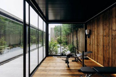 Spor salonunda, güzel yapılmış ahşap duvarlarla tamamlanmış doğal ışığın boşluğu doldurmasına olanak sağlayan bol miktarda pencere bulunuyor.