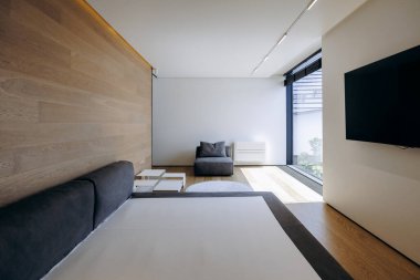 Mekan rahat bir yatak odası, şık bir sandalye, eğlence için bir televizyon ve doğal ışık getiren büyük bir pencere.