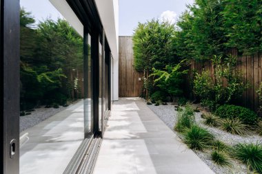 Büyük sürgülü cam kapıların bulunduğu bir eve doğru giden güzel bir yürüyüş yolu var. Açık alana kolay erişim sağlıyor.