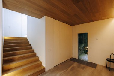 Zarif ahşap merdivenlerle döşenmiş ve ahşap tavanla tamamlanmış güzel tasarlanmış bir koridor.