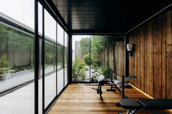 Spor salonunda, güzel yapılmış ahşap duvarlarla tamamlanmış doğal ışığın boşluğu doldurmasına olanak sağlayan bol miktarda pencere bulunuyor.