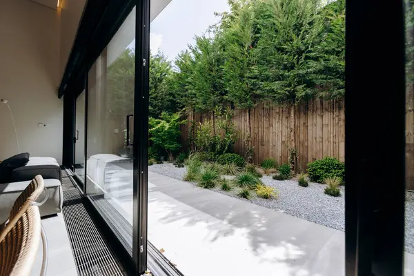 Konforlu bir oturma odasında, dışarıdaki yemyeşil bir bahçeye erişimi sağlayan güzel sürgülü cam kapılar vardır, bu da doğayla kusursuz bir bağ yaratır.