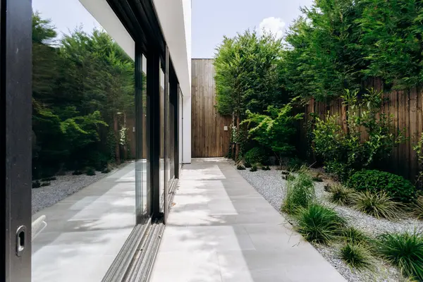 Büyük sürgülü cam kapıların bulunduğu bir eve doğru giden güzel bir yürüyüş yolu var. Açık alana kolay erişim sağlıyor.